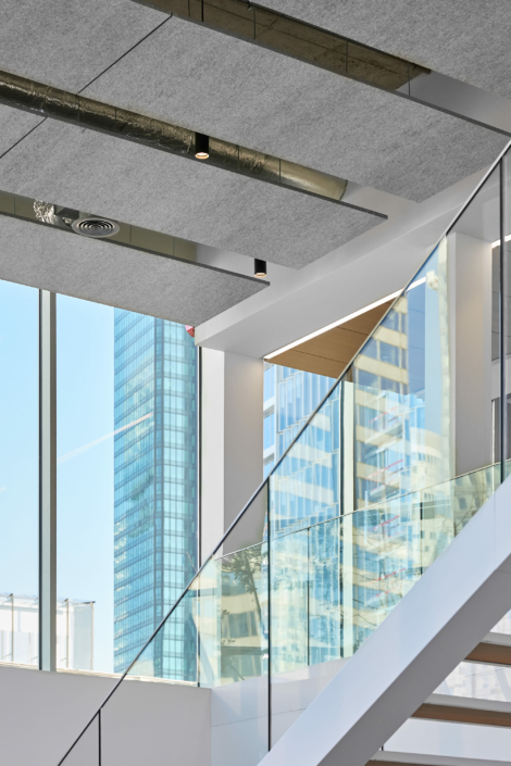Intérieur moderne avec un escalier en verre, de grandes fenêtres et une vue imprenable sur les gratte-ciels extérieurs, offrant une atmosphère aussi vierge et sereine qu'un gymnase acoustique.