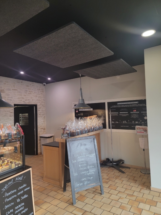 À l'intérieur d'une boulangerie moderne avec des paniers-cadeaux, un menu au tableau noir et des accents de bois éclairés par un éclairage zénithal, l'ambiance évoque une ambiance de restaurant acoustique.