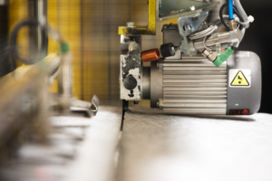 Gros plan d'une machine industrielle coupant ou transformant une feuille de matériau, avec un accent mis sur la machine.