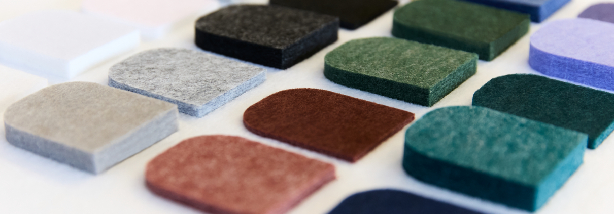 Échantillons de tissus colorés dans des rectangles à bords arrondis, disposés en rangs bien ordonnés sur une surface blanche.