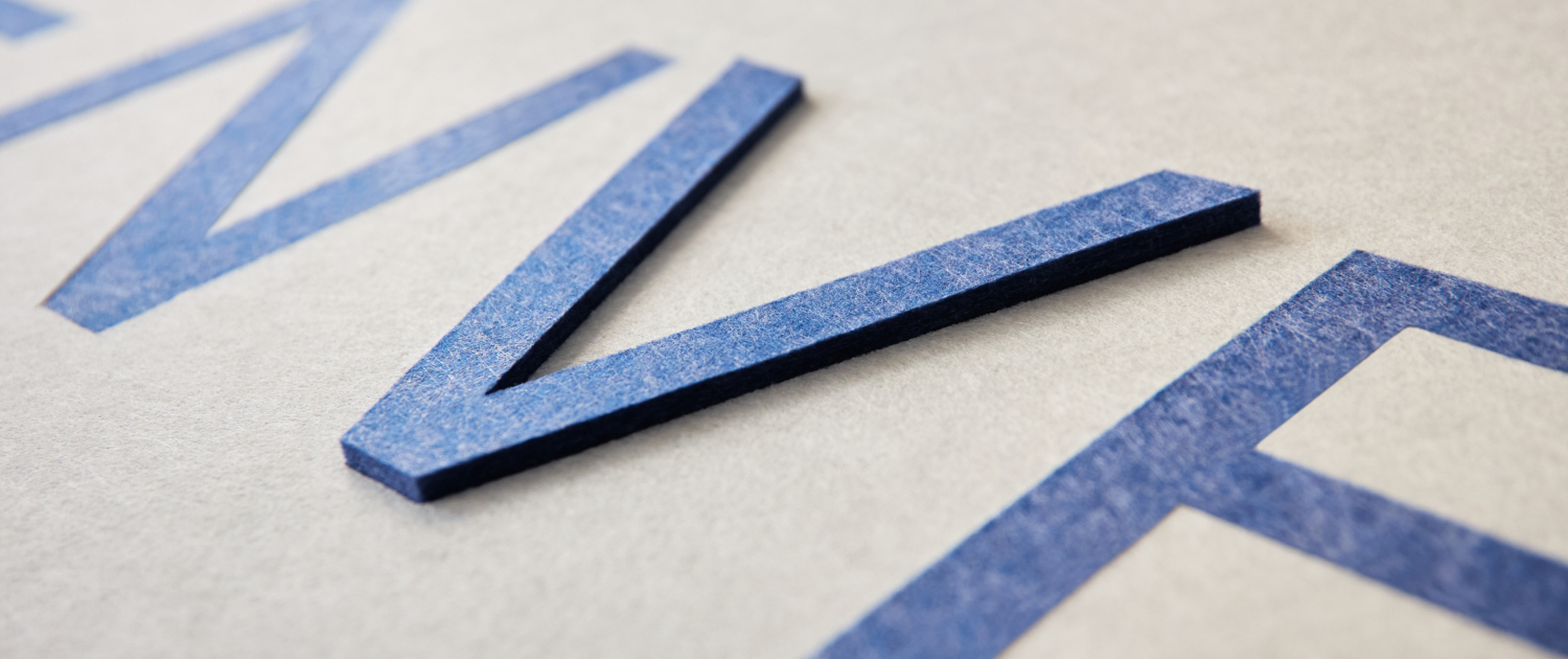 Gros plan sur des lettres bleues, en relief, sans empattement, sur une surface légèrement texturée.