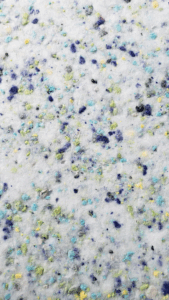 Primo piano di materiale bianco punteggiato di puntini colorati di blu, giallo, verde e viola.
