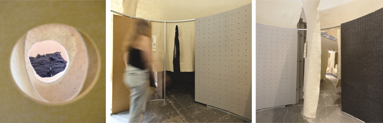 Une femme traverse un espace incurvé, divisé par des cloisons acoustiques aux murs texturés, dont l'un comporte une ouverture circulaire, rappelant le design novateur d'un gymnase.