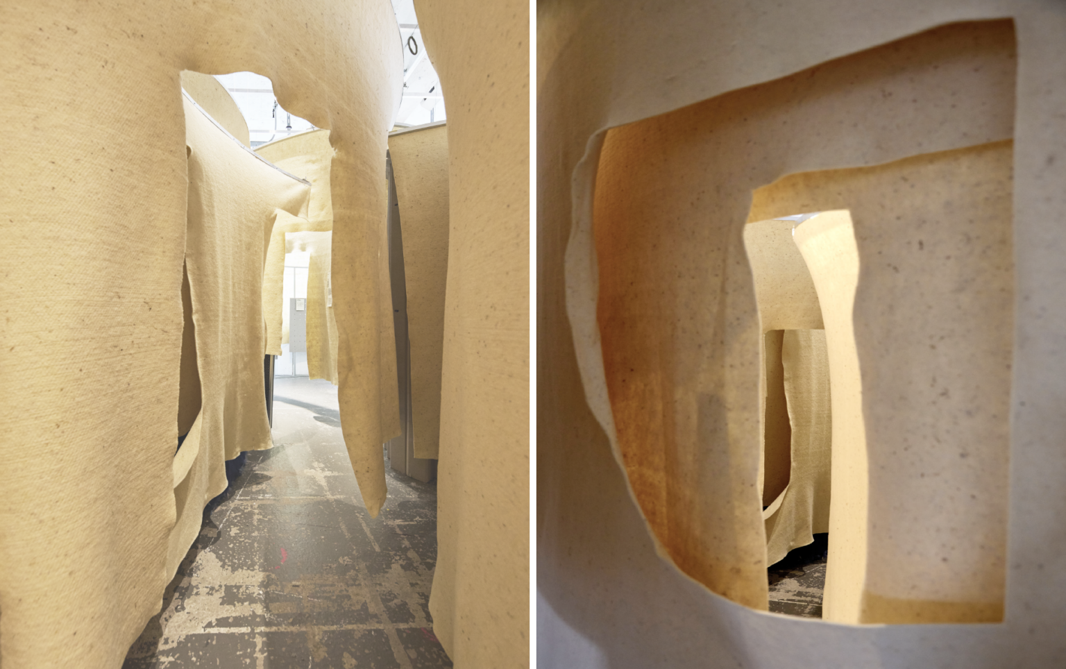 Des allées sinueuses bordées de grandes bandes de tissu texturé de couleur crème suspendues créent une atmosphère immersive, d'inspiration acoustique, dans cette installation artistique installée dans un gymnase couvert.