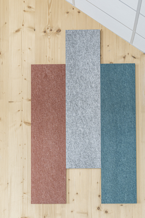 Tre tappeti rettangolari – marrone, grigio e verde acqua – posizionati su un pavimento in parquet chiaro, visti dall'alto, creano un'atmosfera accogliente degna di una palestra.